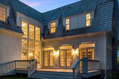 a large white house with lots of windows and lights on it's front porch