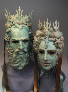 two statues of men with crowns on their heads, one wearing a blue dress and the other green