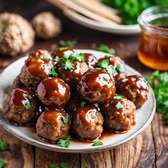 meatballs covered in bbq sauce on a plate with parsley next to it