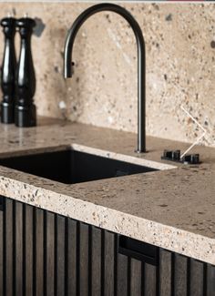 a kitchen sink and faucet with marble counter top in front of black cabinets