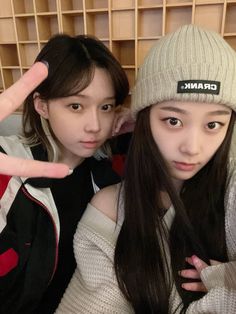 two young women posing for the camera in front of bookshelves with their fingers up