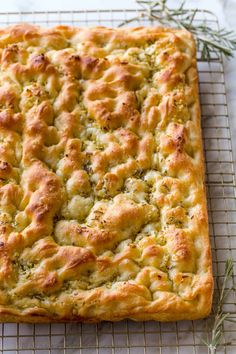 a square pastry on a cooling rack with rosemary sprigs in the top right corner