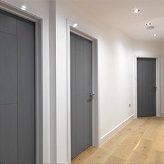 an empty room with three doors and hard wood flooring