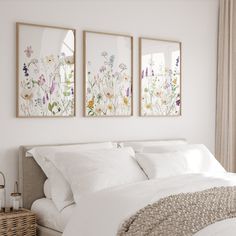 three framed pictures hang on the wall above a bed with white linens and pillows