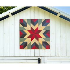 a quilt hanging on the side of a white building with a red and yellow star