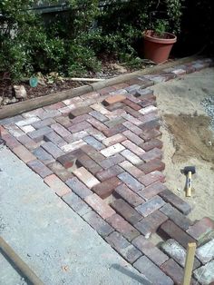 a brick patio being built with tools and bricks on the ground in front of it