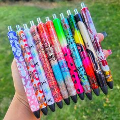 a hand holding a bunch of different colored pens