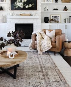 a living room filled with furniture and a fire place in front of a white brick wall