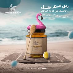 a bottle of honey with a pink flamingo on it and a beach ball in the sand