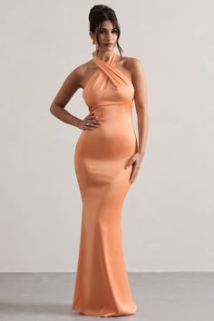 a woman in an orange dress posing for the camera with her hands on her hips