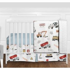 a crib bedding set with construction vehicles on it and a chair in the background