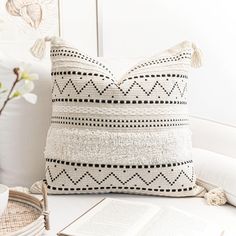 a white pillow sitting on top of a table next to an open book