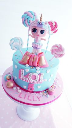 a pink and blue birthday cake decorated with lollipops