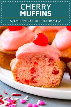 cupcakes with pink frosting and cherries on a plate next to sprinkles