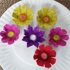 paper plate with flowers on it sitting on carpeted floor next to white plate holding red, yellow and purple flowers