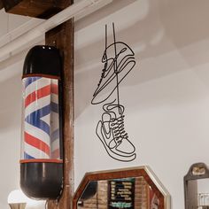 a pair of sneakers hanging on the wall next to a mirror and lamp in a room