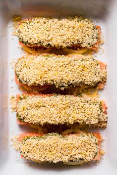 four fish fillets are lined up in a baking dish with parmesan cheese on top