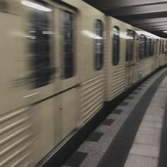 the train is moving fast through the subway station with its doors open and people standing on the platform