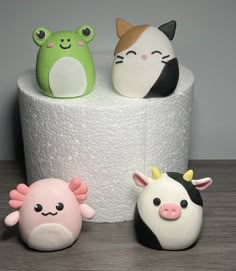 three small toy animals sitting on top of a roll of toilet paper next to each other