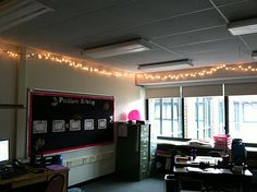 an office with lights strung from the ceiling and computer desks in front of it