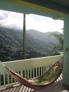 a hammock on a porch with mountains in the background