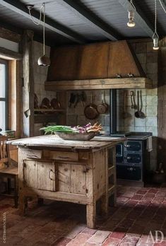 a rustic kitchen with an old stove and wooden table in the center, surrounded by brick flooring