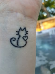 a small tattoo on the wrist of a person with a cat and heart in it