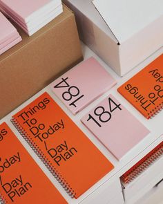 several orange and pink sticky notes sitting on top of a white table next to boxes