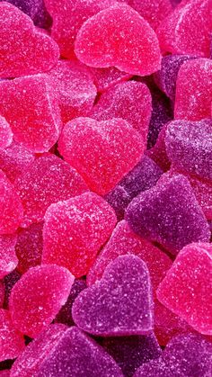 pink and red heart shaped candies are in the middle of purple and red candy