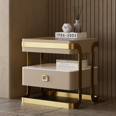 a white and gold side table with two drawers on each shelf, next to a wall