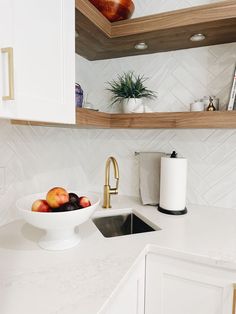 a bowl of fruit sitting on top of a kitchen counter