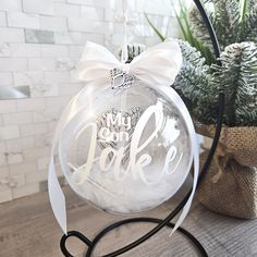 a glass ornament with a bow on it sitting next to a potted plant