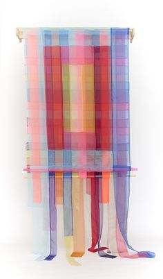 an abstract painting with multicolored squares and ribbons hanging on a wall in front of a white background