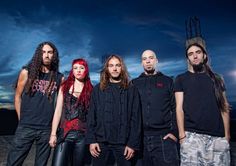 five people standing in front of a dark sky with the sun setting behind them and one person has long red hair