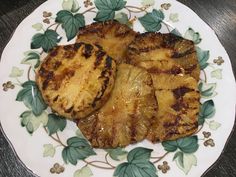 two pieces of pineapple sitting on top of a white and green flowered plate