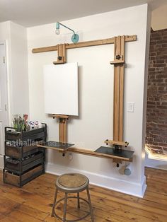 an empty room with two easels, a stool and a white board on the wall