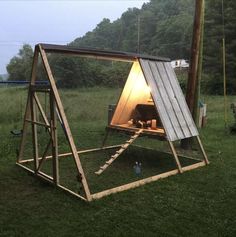 a chicken coop in the middle of a grassy field with a light on it's roof