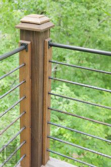 a wooden and metal railing with trees in the background