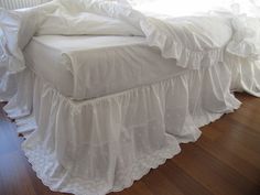 a bed with white ruffled bedspread and pillows