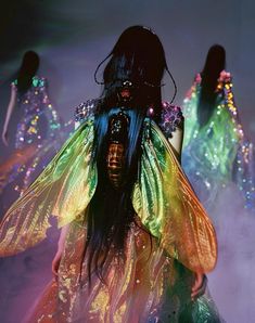 a woman with long black hair and colorful wings on her body