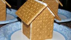 three small houses made out of graham crackers on blue and white plates with decorative designs