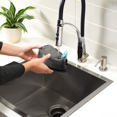 a person is washing their hands in the kitchen sink with a soap dispenser