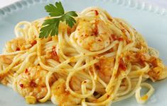 a pasta dish with shrimp and sauce on a blue plate, garnished with parsley