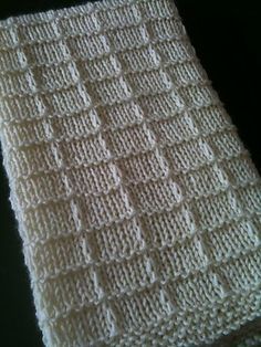 a white knitted dishcloth sitting on top of a table next to a black surface