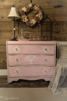 a pink dresser sitting next to a lamp