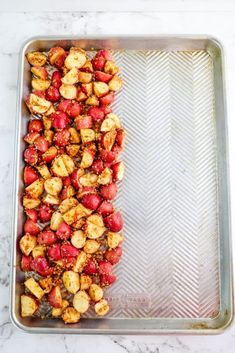 roasted strawberries and potatoes in a baking pan on a marble counter top with a silver tray