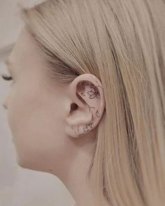 a woman's ear is decorated with flowers and has a small flower tattoo on it