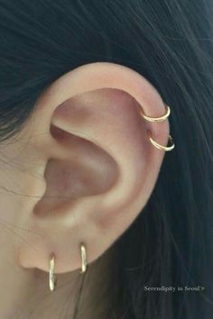 a woman's ear is shown with two small hoops attached to the side