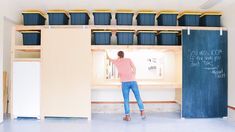 a woman standing in front of a chalkboard with blue bins on the wall