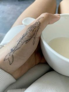 a person with a tattoo on their arm next to a bowl of milk and a spoon